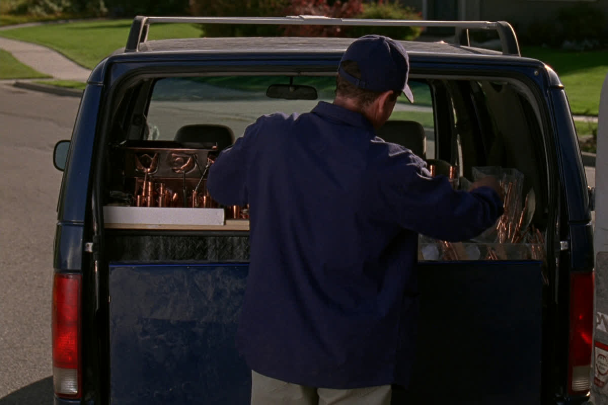 Tradesman organizing copper fittings at the back of his work van