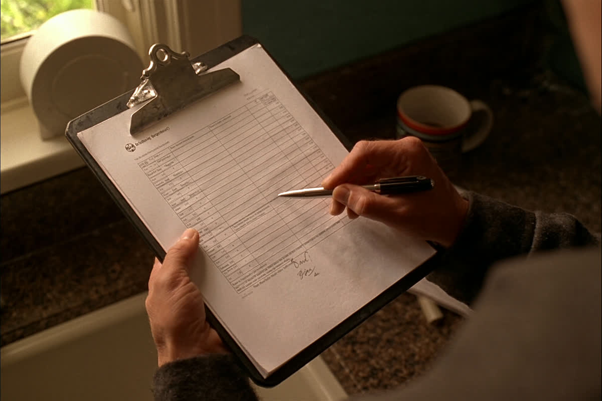 Plumber going over a written estimate on a clipboard at a kitchen counter