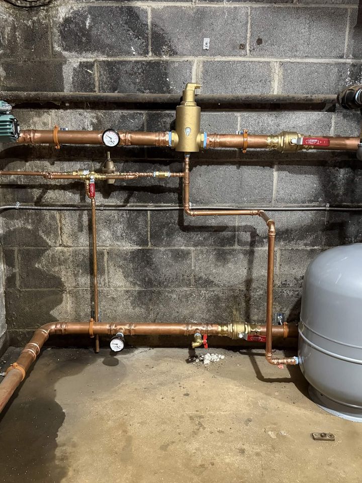 Basement copper repipe with a new backflow preventer, gauge and expansion tank on a block wall