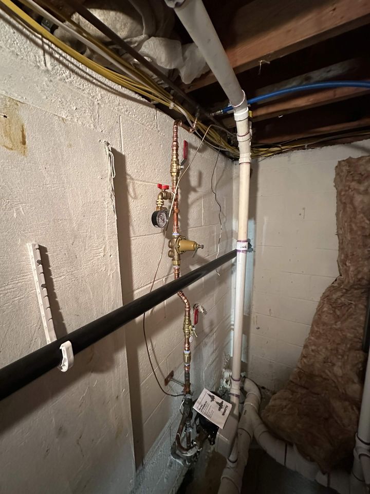 Copper water line stub-outs run along a basement wall