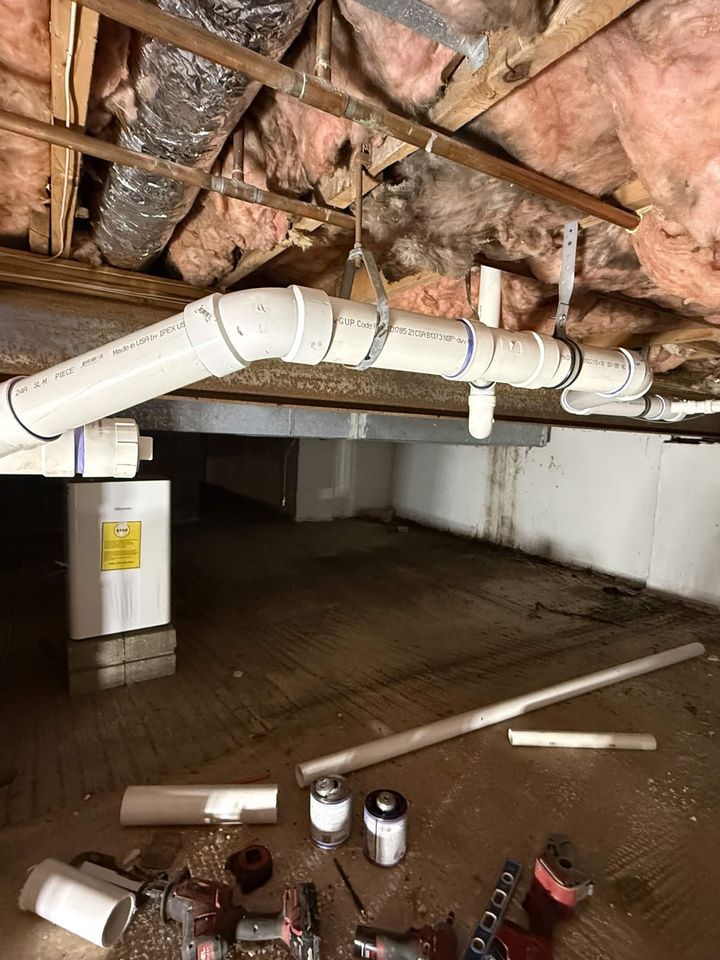 New PVC drain lines run through a crawlspace