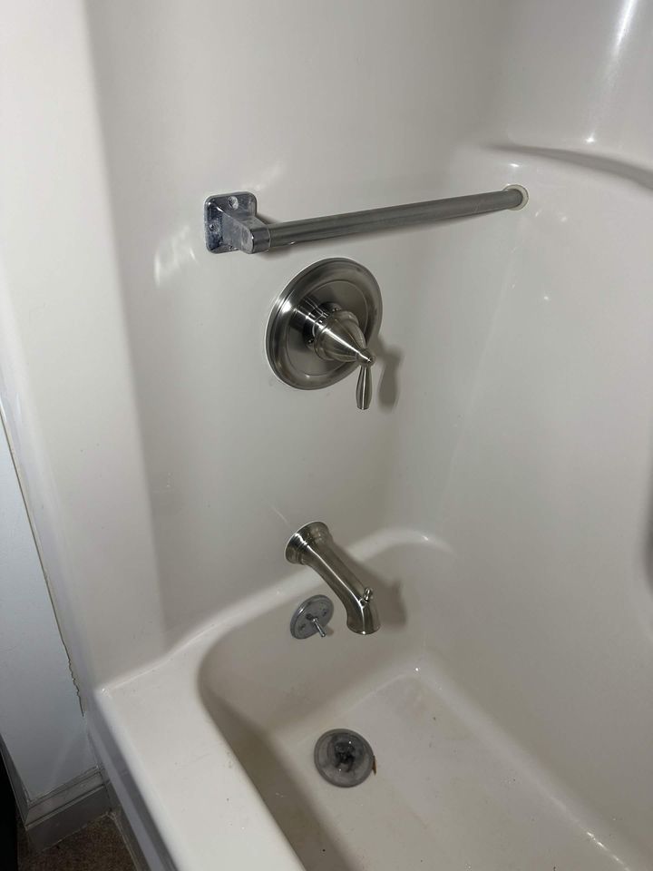 New tub and shower valve with brushed nickel trim and tub spout in a finished bathroom