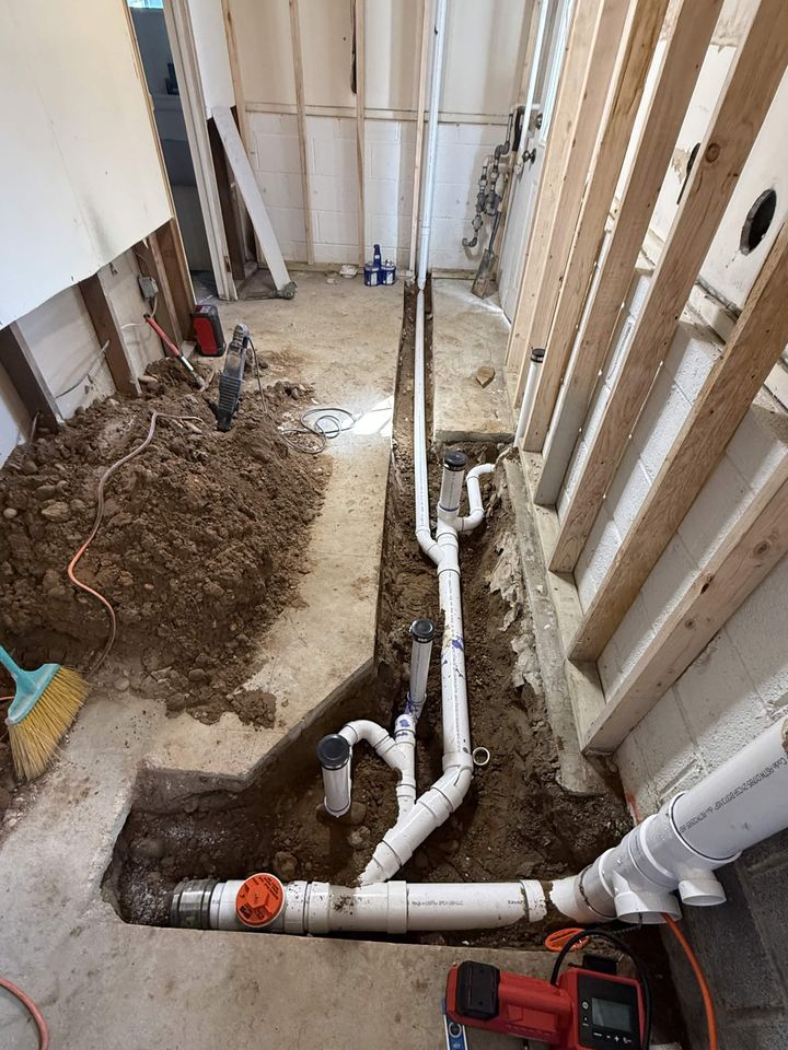 New PVC drain lines set into a trenched basement slab during a bathroom addition