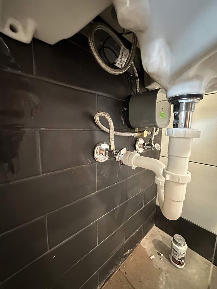 New vanity drain and P-trap with braided supply lines in a tiled bathroom